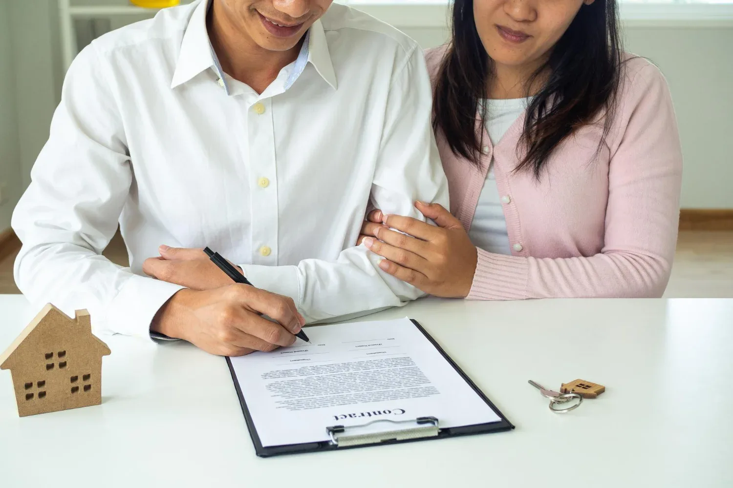 Casal assinando contrato entre locador e locatário para aluguel de imóvel